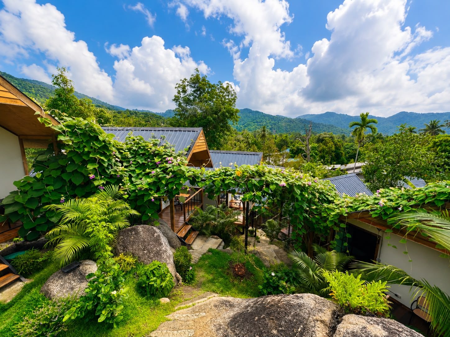 Green hills and tropical garden around the bungalows under a blue sky