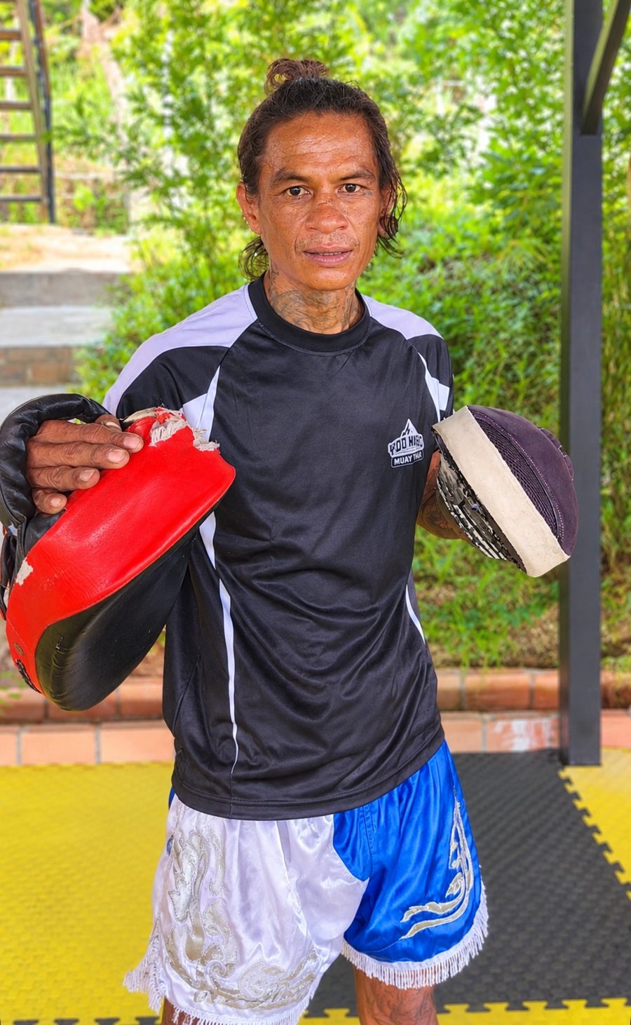Kru Baw holding Muay Thai pads at the gym